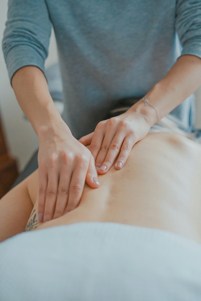 A massage therapist's hands working a patient's upper back