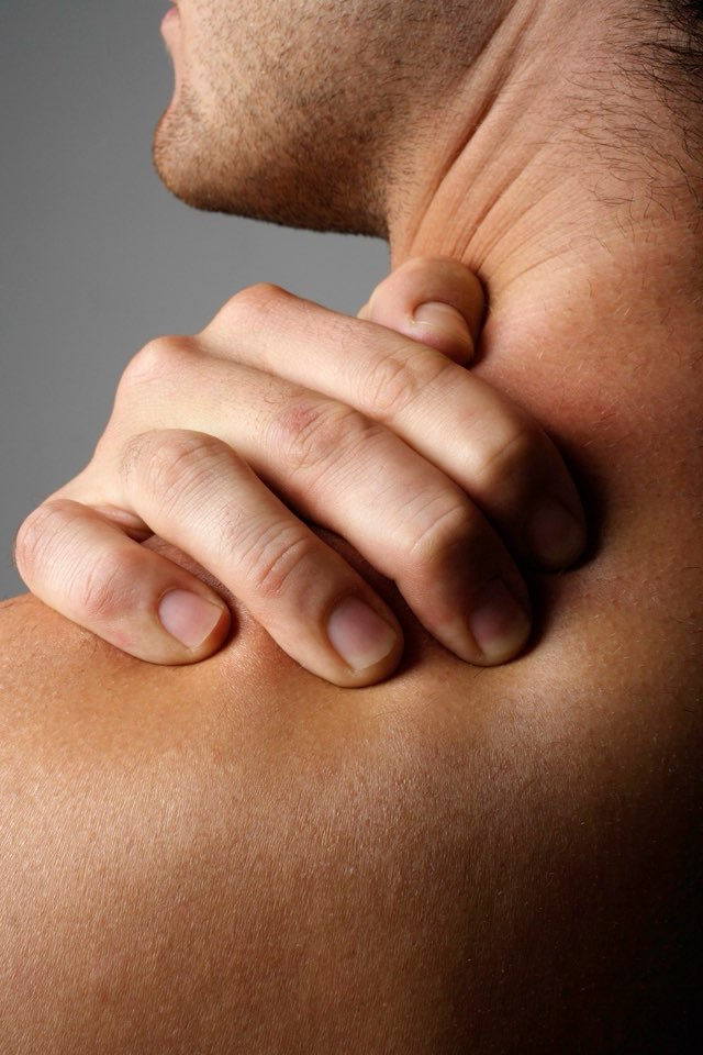 A man gripping the back of his neck in pain